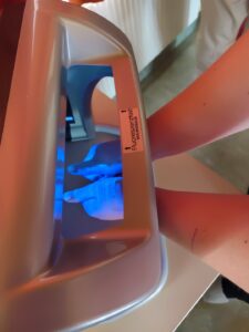 Hände leuchten unterschiedlich blau unterm Fluoreszenztester
