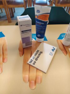 2 Handcremen, ein Brillenputztuch und ein Folder in Handform von der AUVA