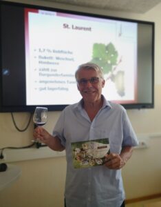 Weinverkostung 2022_3EH7 (4) Alfred Liling von der Weinakademie mit Glas und Broschüre und St. Laurent im Wein