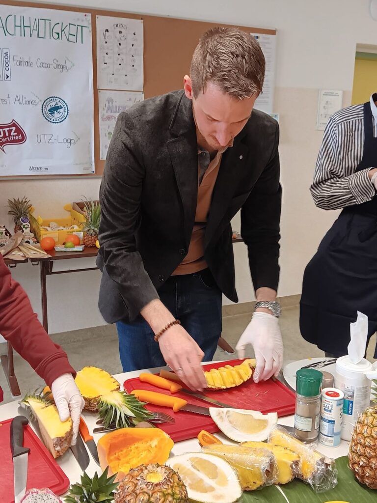 Ein Mann arrangiert eine geschnittene Ananas für eine fachgerechte Präsentation füreine Verkostung