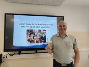 Robert Kamleiter, Biersomelier von der Privatbrauerei Zwettler hält ein Glas Bier vor der Tafel mit der Powerpoint Folie "Vielen Dank für die Aufmerksamkeit und viel Spaß beim Verkosten"
