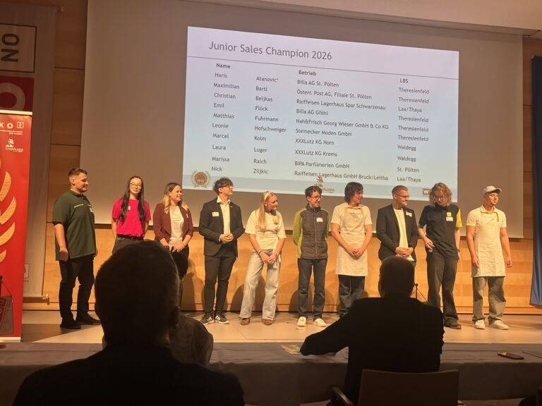 Zehn Kandidatinnen und Kandidaten des Junior Sales Champion 2026 stehen auf der Bühne, dahinter eine Beamerprojektion an der Wand mit deren Namen