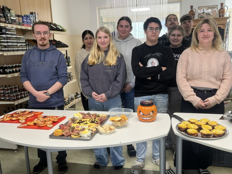 Neun Schülerinnen und Schüler stehen hinter den Tischen mit den für die Verkostung vorbereiteten Platten mit Fingerfood